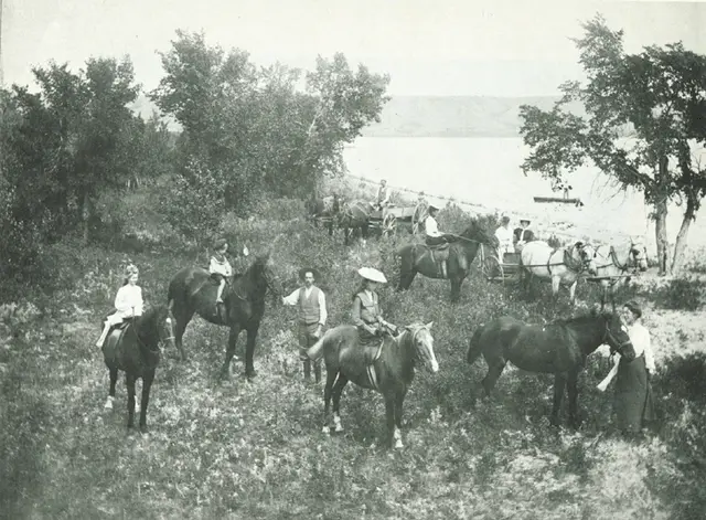 Horseback riders and wagons by the lake
