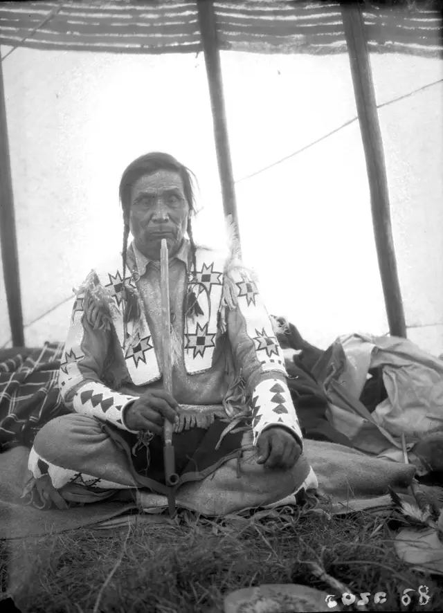 Squatipew of the Star Blanket Band seated in a tent with a pipe