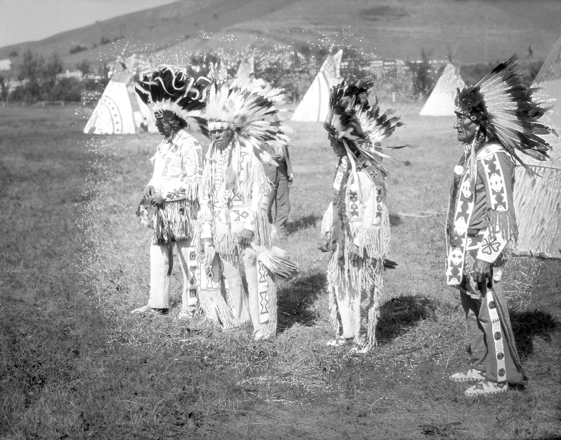 Plains Cree men in regalia at a powwow camp